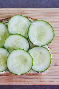 Dilimlenmiş salatalıklı sandviç vegan mayonezli kesim tahtası, basit, sağlıklı malzemeler kavramı.