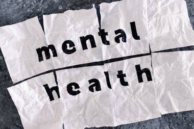 Yapışkan bant, psikoloji ve duygusal iyileşme kavramlarıyla birleştirilmiş buruşmuş ve yırtılmış kağıt parçaları üzerine zihinsel sağlık metni