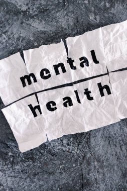Yapışkan bant, psikoloji ve duygusal iyileşme kavramlarıyla birleştirilmiş buruşmuş ve yırtılmış kağıt parçaları üzerine zihinsel sağlık metni