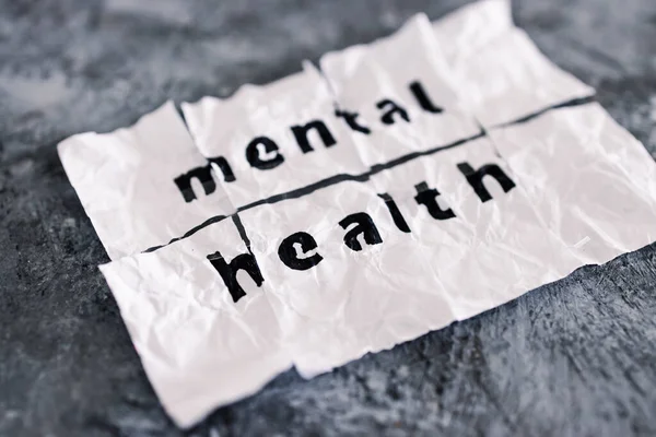 Mental health text on crumpled and torn piece of paper which has been reassembled with sticky tape, concept of psychology and emotional healing