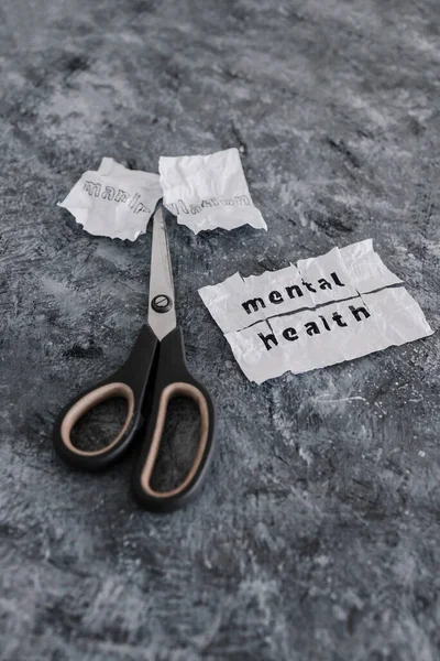 Manipulation text on crumpled piece of paper which is getting cut with scissors next to Mental Health text, concept of psychology and emotional strength to deal with toxic behaviours