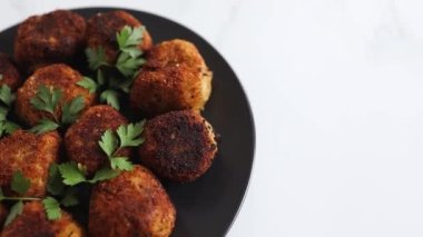 Vejetaryen pesto arancini kızarmış risotto topları üzerine taze maydanoz, sağlıklı bitki temelli yemek tarifleri.