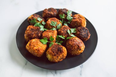 Vejetaryen pesto arancini kızarmış risotto topları üzerine taze maydanoz, sağlıklı bitki temelli yemek tarifleri.
