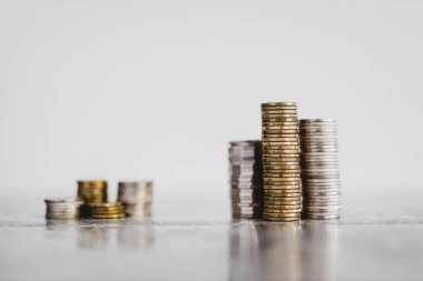 Beyaz arka planda küçük ve büyük bir gruba bölünmüş farklı madeni para yığınları, iyi ve kötü yatırımlar kavramı veya yatırım öncesi ve sonrası