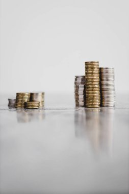 Beyaz arka planda küçük ve büyük bir gruba bölünmüş farklı madeni para yığınları, iyi ve kötü yatırımlar kavramı veya yatırım öncesi ve sonrası