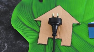 konut simgesi yeşil yaprak üzerinde Avustralya fişi yanında ödeme kartları, yenilenebilir enerji kavramı ve güneş enerjisi gibi temiz enerji kaynakları