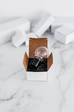 Beyaz kutunun üstünde minimalist beyaz mermer arka planda ampul fikri olan kutu kavramının dışında düşünün.