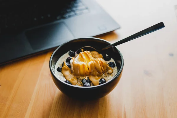 Mango Blaubeeren Haferflocken Essen Während Man Von Hause Aus Laptop — Stockfoto