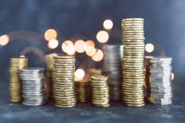 Peri ışığı, bolluk kavramı ve tasarruf hedeflerinize ulaşmak ile karanlık arka planda büyük miktarda tasarruf vuruşu oluşturan farklı altın ve gümüş madeni paralar yığını