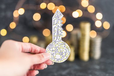 Peri ışıkları, kripto para ve dijital ödemeler veya yatırımlar kavramı olan farklı madeni para yığınlarının önünde el ele tutuşan dijital anahtar
