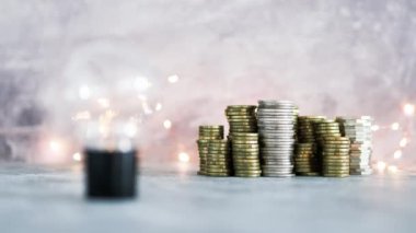 Fikir ampulü farklı altın ve gümüş para yığınları ile büyük miktarda para temsil ediyor. Peri ışığı, başarı ve bolluk kavramı ile gri beton arka planda çekim yapmak.