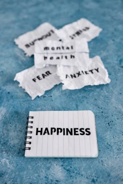 Yırtık bantlanmış sayfa, psikoloji ve engelleri aşma konseptiyle ilgili zihinsel sağlık metninin yanında Korku Korkusu Stres ve Yanık Sözcükler ile notlarda mutluluk metni