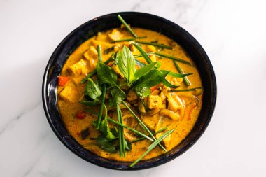 Çan biberli vejetaryen tofu körisi ve taze otlarla kaplı karışık sebzeler ve baharatlar, sağlıklı bitki temelli yemek tarifleri.