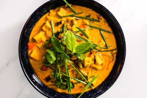 Çan biberli vejetaryen tofu körisi ve taze otlarla kaplı karışık sebzeler ve baharatlar, sağlıklı bitki temelli yemek tarifleri.