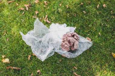 Plastik torbalar ve çöpler yeşil çimlerde terk edilmiş, çevreye saygı duyma ve tek kullanımlık plastikten kaçınma kavramı