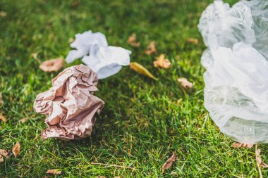 Plastik torbalar ve çöpler yeşil çimlerde terk edilmiş, çevreye saygı duyma ve tek kullanımlık plastikten kaçınma kavramı