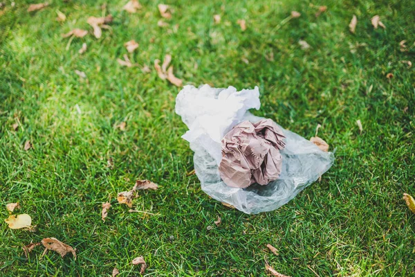 Plastik torbalar ve çöpler yeşil çimlerde terk edilmiş, çevreye saygı duyma ve tek kullanımlık plastikten kaçınma kavramı