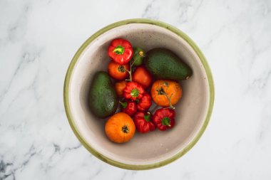 Taze toplanmış domatesli meyve kasesi aocados ve mini dolmalık biber, basit doğal sağlıklı malzemeler konsepti.