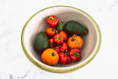 Taze toplanmış domatesli meyve kasesi aocados ve mini dolmalık biber, basit doğal sağlıklı malzemeler konsepti.