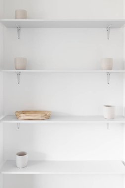 Minimalist beyaz duvar rafları beyaz saksıları ve ahşap tepsileri olan bir oyuk, modern iç tasarım konsepti ve basit ev geliştirmeleri