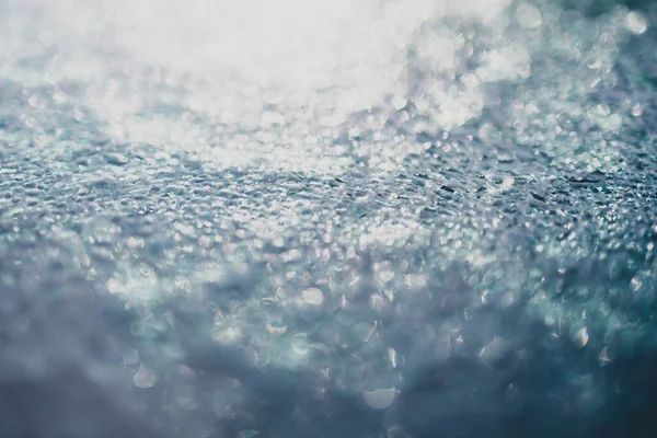 Doğal ışık altında dokulu camların üzerine yağmur damlaları düşer. Son derece sığ bir alan derinliğinde çekilir.