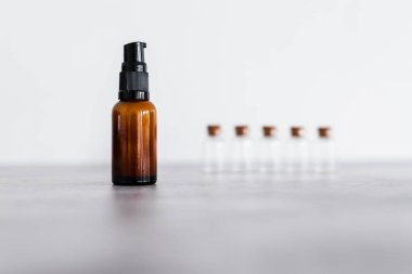 Kehribar cilt bakımı şişesi. Arka planda küçük malzeme şişeleri var. Doğal güzellik kavramı ve organik malzemeler.