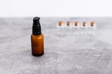 Kehribar cilt bakımı şişesi. Arka planda küçük malzeme şişeleri var. Doğal güzellik kavramı ve organik malzemeler.