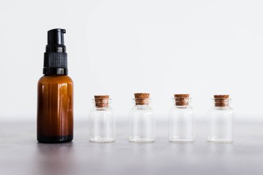 amber skincare bottle with small bottles of ingredients inext to it, concept of natural beauty and organic ingredients in skincare