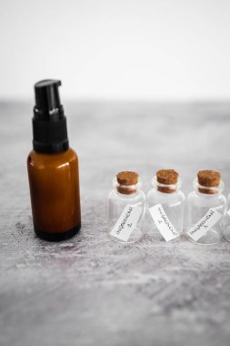 amber skincare bottle with small bottles of ingredients inext to it, concept of natural beauty and organic ingredients in skincare