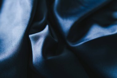 luxurious navy blue silk or satin fabric close-up for bedding or clothes, with soft wrinkle and light shining on it 