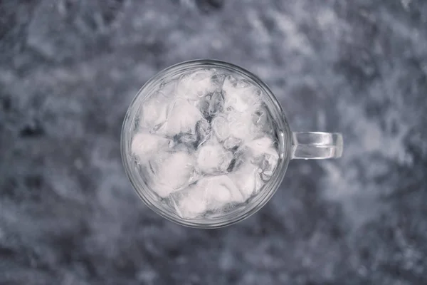 灰色のコンクリートの背景に水道水と氷のキューブを持つピントガラス 十分な水や酸味を飲むという概念 — ストック写真