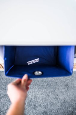 İçinde Declutter etiketi olan el kutusunu almak ve arka planda başka sepetler bulunan odaksız depolama dolabı, evinizi düzenleme ve azaltma kavramı