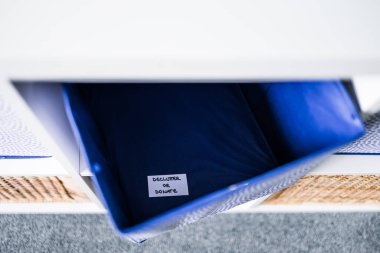 Dornatif etiketli bir depolama küpü. Arka planda başka sepetler bulunan odaksız bir depolama dolabı. Evinizi düzenleme ve küçültme kavramı.