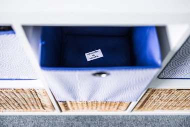Dornatif etiketli bir depolama küpü. Arka planda başka sepetler bulunan odaksız bir depolama dolabı. Evinizi düzenleme ve küçültme kavramı.
