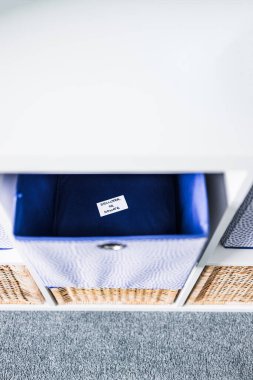 Dornatif etiketli bir depolama küpü. Arka planda başka sepetler bulunan odaksız bir depolama dolabı. Evinizi düzenleme ve küçültme kavramı.