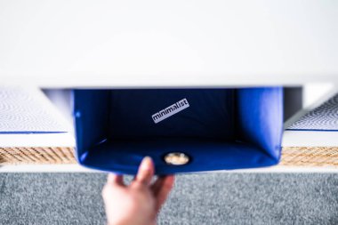 Minimalizm etiketli el bilgisayarı kapmak ve arka planda başka sepetler bulunan odaksız depolama dolabı, düşme ve evinizi düzenleme kavramı