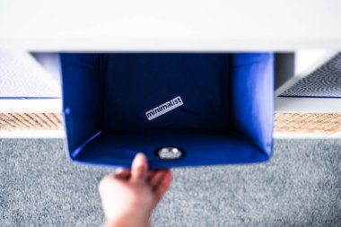 Minimalizm etiketli el bilgisayarı kapmak ve arka planda başka sepetler bulunan odaksız depolama dolabı, düşme ve evinizi düzenleme kavramı