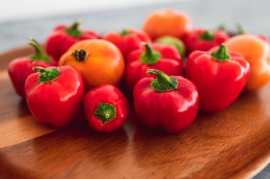 Tahta tepside canlı kırmızı ve turuncu renkte domatesler ve yeni toplanmış mini capsiumlar, basit doğal sağlıklı malzemeler kavramı.
