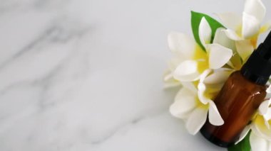 natural beauty and organic ingredients in skincare, apothecary skincare bottle with tropical frangipani flowers in the background