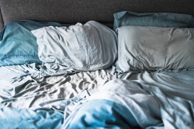 dağınık ve dağınık görünümlü, açık mavi yorgan ve çarşaflı kraliçe yatağı uykunuzu veya çift yaşam konseptinizi geliştirir.