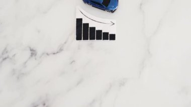 Araba kredileri, araba fiyatları yükseliyor, mavi oyuncak araba, istatistiklerin yükseldiğini gösteren grafiğin yanındaki mermer arka planında