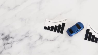 Araba kredileri, araba fiyatları yükseliyor, mavi oyuncak araba, istatistiklerin yükseldiğini gösteren grafiğin yanındaki mermer arka planında