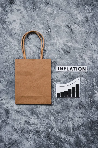 物価が上昇していることを示すグラフのショッピングバッグの上にテキストで経済の概念的なイメージを停滞させ — ストック写真