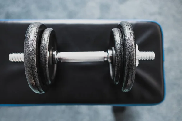 home gym and fit lifestyle still-life, room with flat abs bench and dummbell on top of it shot at shallow depth of field with desaturated moody tones