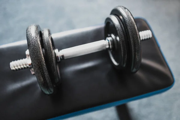 home gym and fit lifestyle still-life, room with flat abs bench and dummbell on top of it shot at shallow depth of field with desaturated moody tones