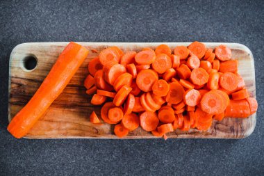 Tahta doğrama tahtasının üzerinde taze havuçların dilimlendiği yakın plan çekimler, basit, sağlıklı malzemeler kavramı.