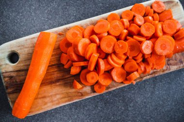 Tahta doğrama tahtasının üzerinde taze havuçların dilimlendiği yakın plan çekimler, basit, sağlıklı malzemeler kavramı.