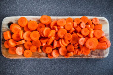 Tahta doğrama tahtasının üzerinde taze havuçların dilimlendiği yakın plan çekimler, basit, sağlıklı malzemeler kavramı.