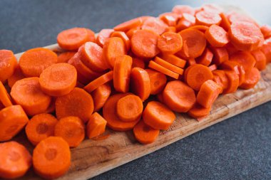 Tahta doğrama tahtasının üzerinde taze havuçların dilimlendiği yakın plan çekimler, basit, sağlıklı malzemeler kavramı.