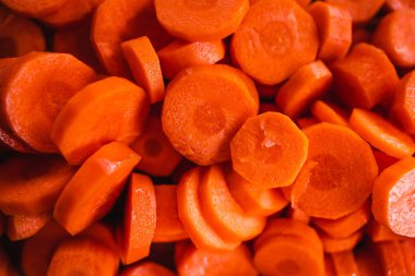 Tahta doğrama tahtasının üzerinde taze havuçların dilimlendiği yakın plan çekimler, basit, sağlıklı malzemeler kavramı.